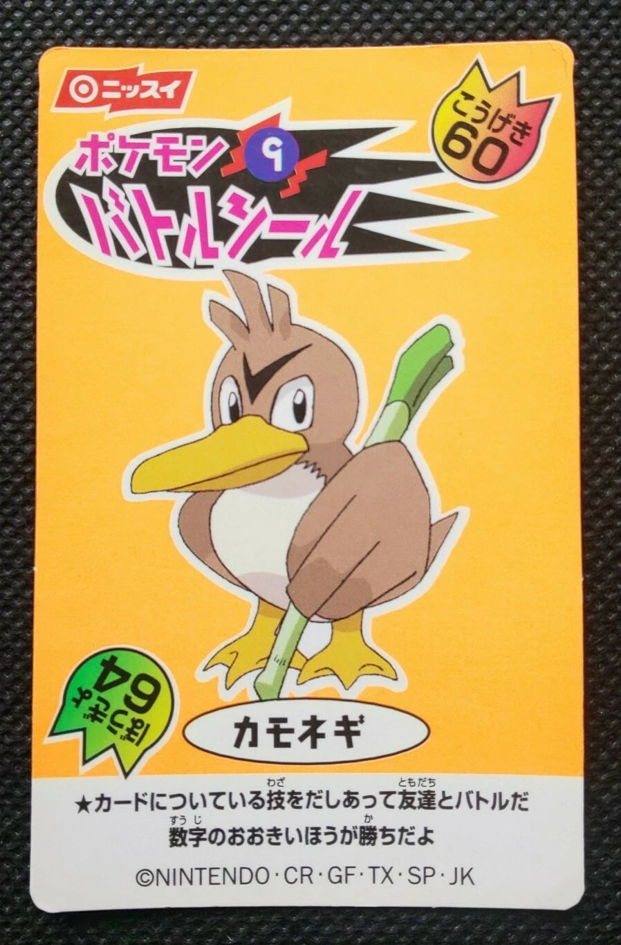 A 1999 Nissui Pokémon Battle Seal featuring Farfetch'd on a plain orange background